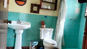 Een badkamer met een wastafel op een voetstuk, toilet en douche.