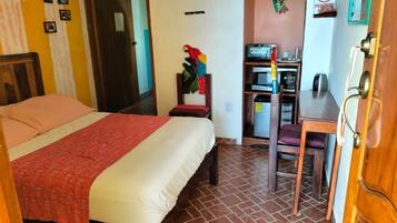 A bedroom with a bed, a desk, and a microwave.