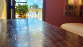 A wooden table with a view of a balcony and a plant.