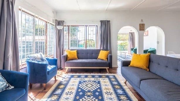 A spacious living room with a grey sofa, blue armchairs, and a patterned rug.