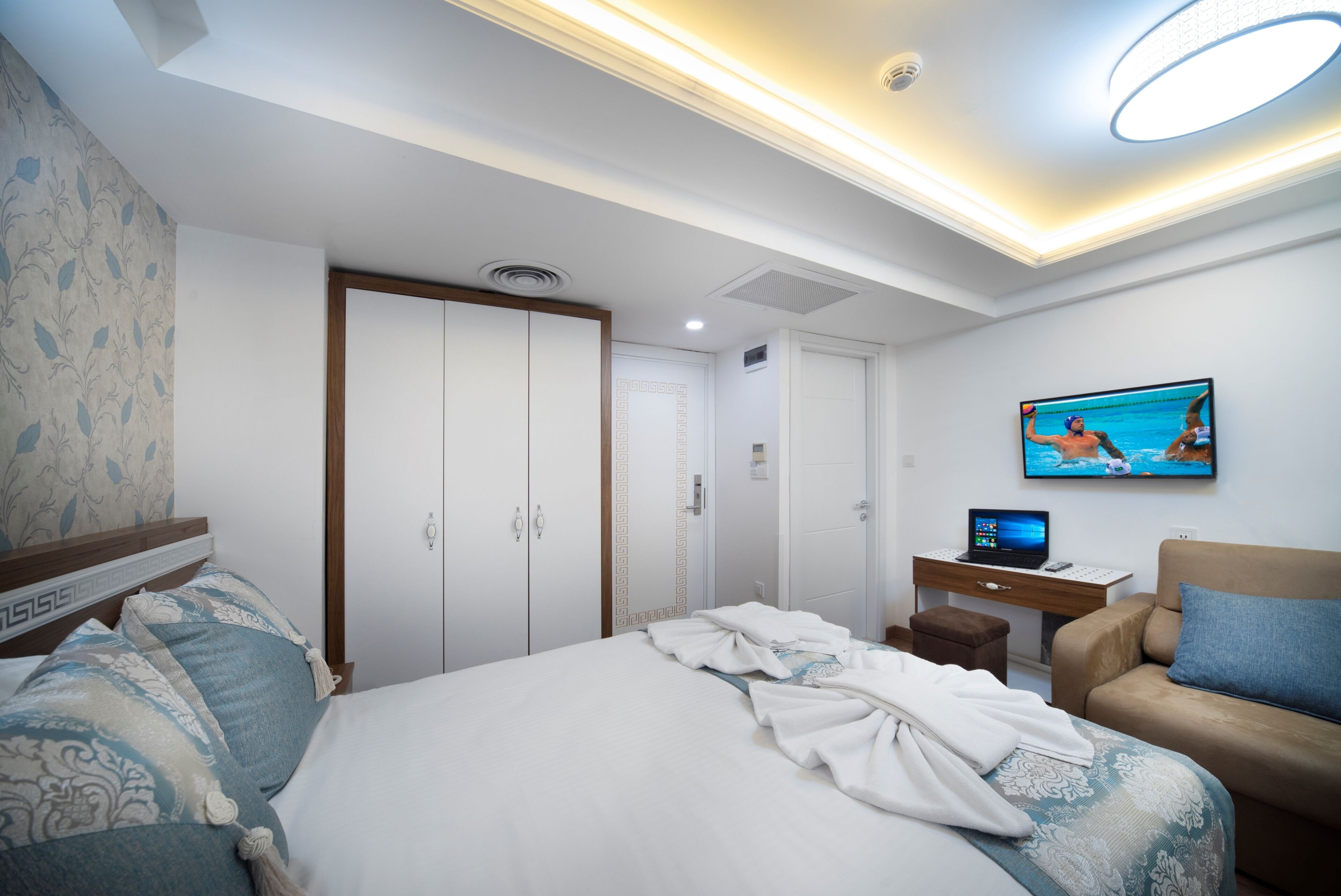 A hotel room with a bed, a desk, a television, and a sofa.