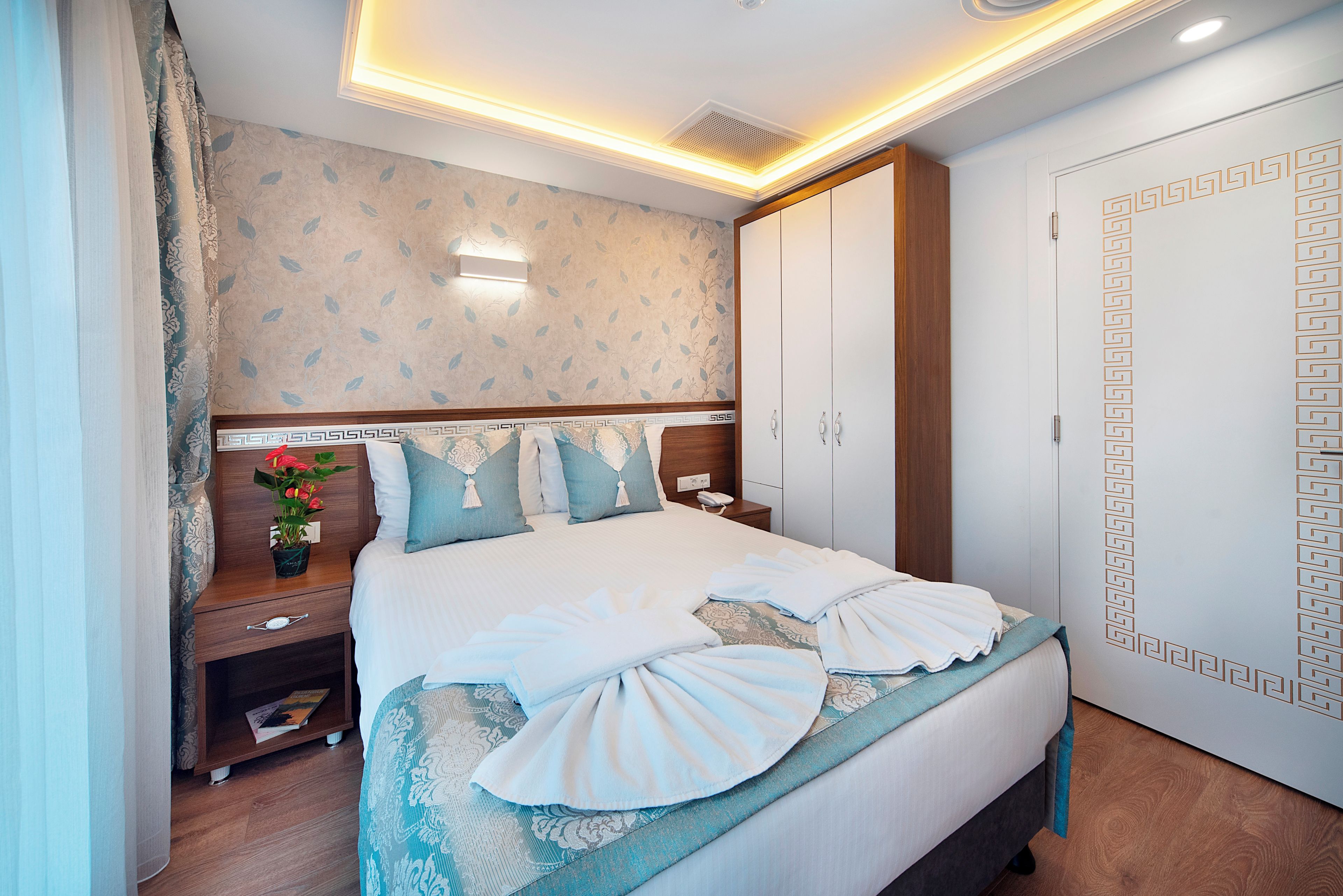 A hotel room with a bed, bedside table, lamp, and a wardrobe.