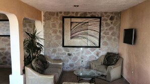 A living room with a stone wall, a glass coffee table, and two sofas. - Teques Vacation Home, Golden Zone "Las Alas" Lake View (Tequesquitengo)