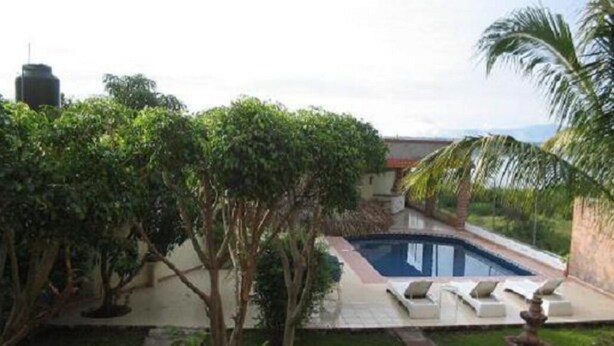 A private pool area with lounge chairs, surrounded by greenery and a stone pathway. - Teques Vacation Home, Golden Zone "Las Alas" Lake View (Tequesquitengo)