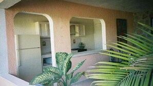 A small kitchen with white cabinets and a refrigerator. There are two archways leading into the kitchen, and a plant is visible in the foreground. - Teques Vacation Home, Golden Zone "Las Alas" Lake View (Tequesquitengo)