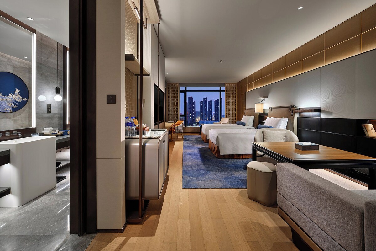 Une chambre d’hôtel moderne avec vue sur la ville, un coin salon et un espace repas séparé.