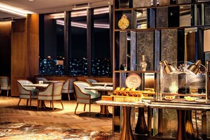 Un espace repas moderne avec vue sur la ville, doté de meubles en bois et d’une cloison décorative en verre.