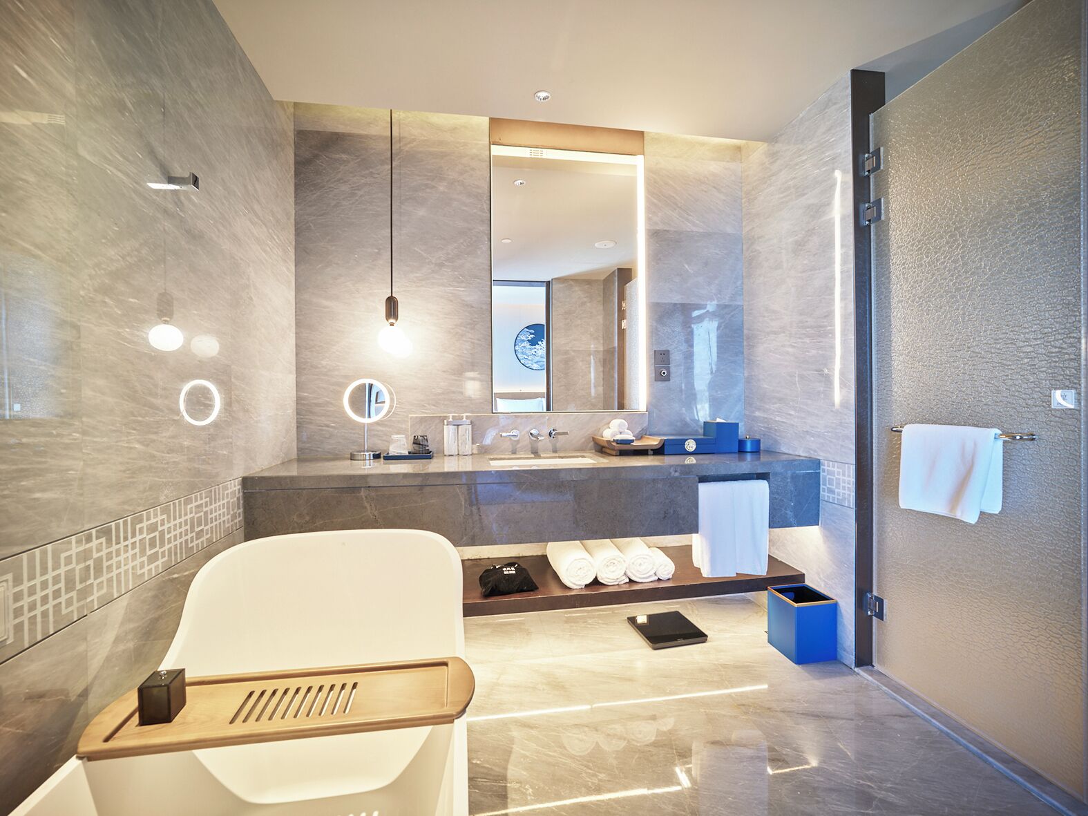 Une salle de bain moderne avec un grand miroir, une baignoire et un meuble-lavabo doté d’un évier et d’un porte-serviettes.