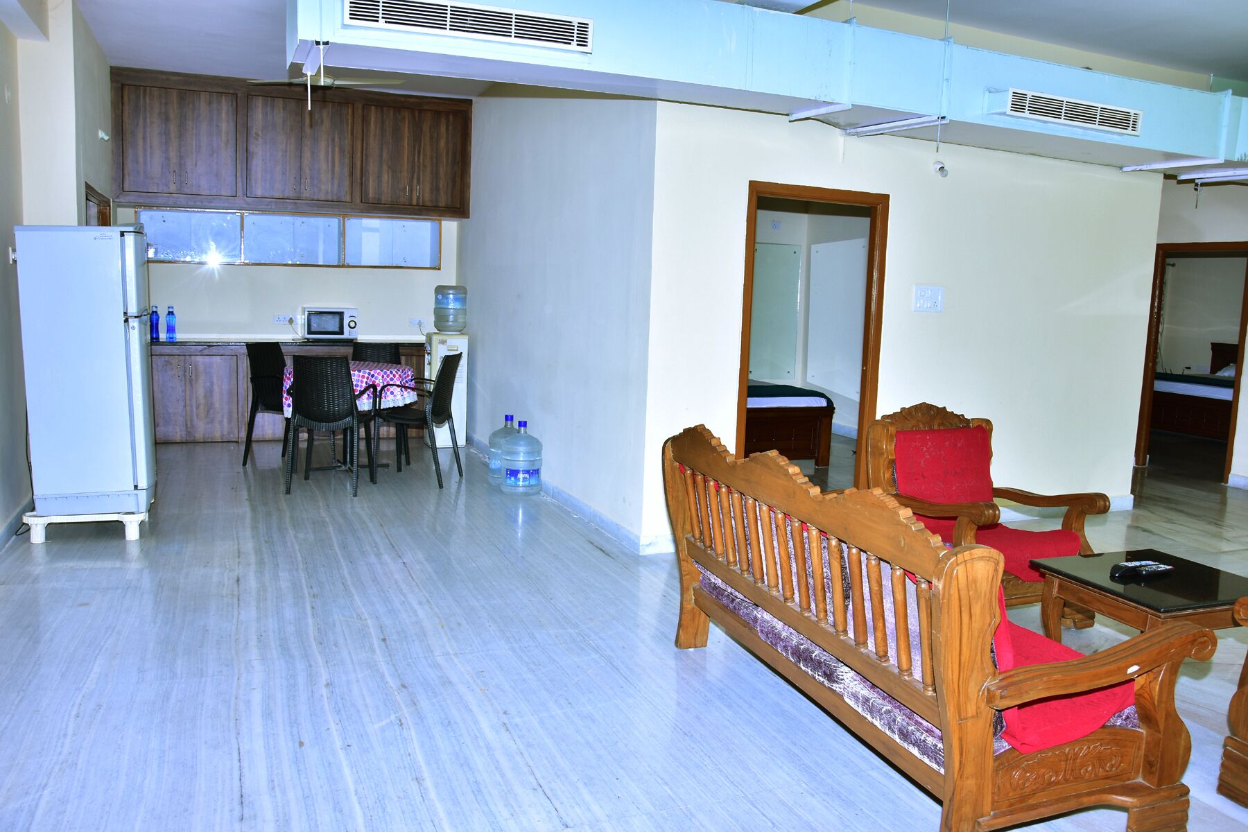 A compact living space with a kitchenette, a dining area, and a seating area with a wooden bench and chairs.