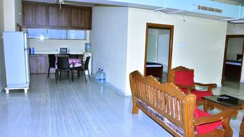 A compact living space with a kitchenette, a dining area, and a seating area with a wooden bench and chairs.
