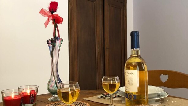 A dining table with a loaf of bread, two glasses of wine, a vase with a red rose, and candles. - LES ARCADES in the heart of the medieval city of Sarlat (Sarlat-la-Canéda)