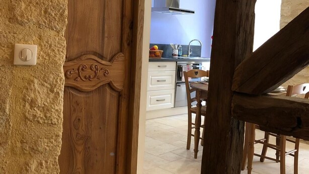 Un interior rústic amb una porta de fusta, una zona de menjador i una cuina amb electrodomèstics moderns.