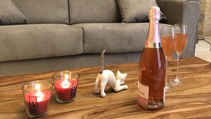 Taula de fusta amb una ampolla de vi rosat, dues copes i dues espelmes enceses.