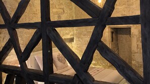 Un interior rústic amb bigues de fusta al descobert, una paret de pedra i una làmpada penjant.