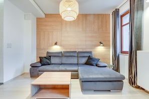 A modern living room with a sectional sofa, a coffee table, and a wooden accent wall.