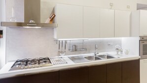 Eine moderne Küche mit Gasherd, Spüle aus Edelstahl und weißen Schränken.