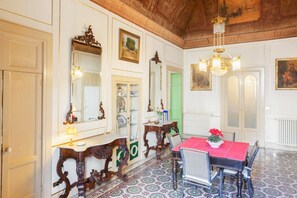 Un comedor con una mesa, sillas, una araña y una puerta verde.