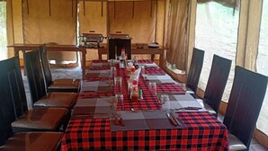 A dining area with a checkered tablecloth, wooden chairs, and a central table with condiments and cutlery.