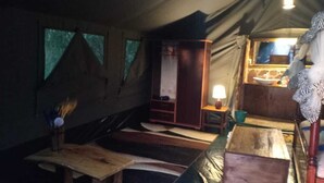 A tent with a wooden table, a bench, and a small cabinet.