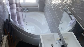 A modern bathroom with a large bathtub, a separate shower area, and a vanity with a mirror.