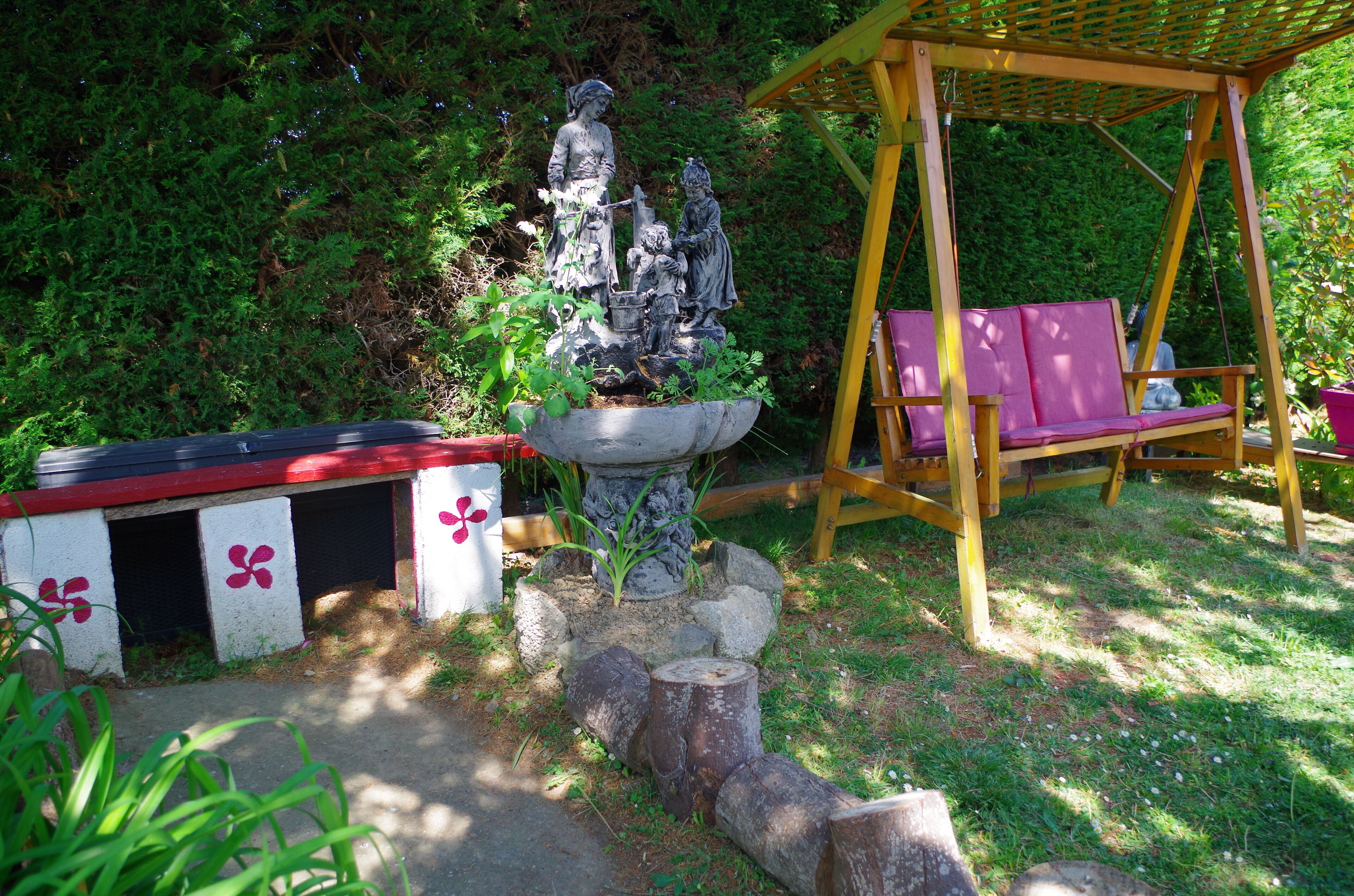 A garden with a statue, a wooden swing, and a bench.