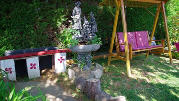 A garden with a statue, a wooden swing, and a bench.