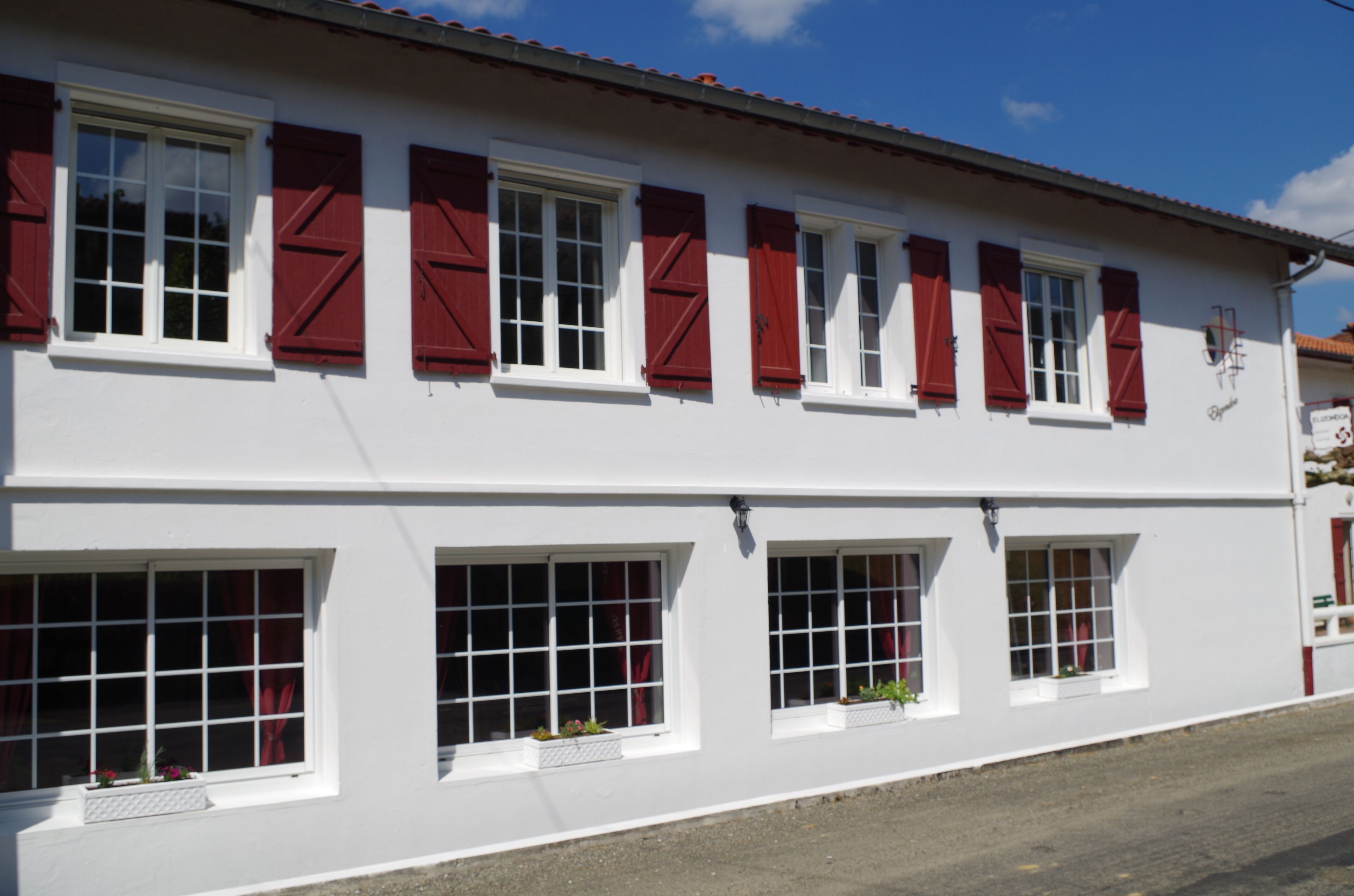 Un edificio blanco con contraventanas rojas y numerosas ventanas.