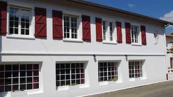 Un edificio blanco con contraventanas rojas y numerosas ventanas.