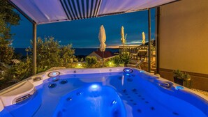 A hot tub with a view of the sea and a covered patio area.