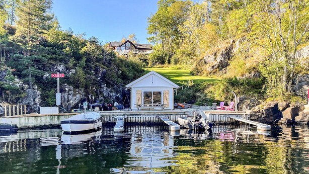 A dock with boats, a gazebo, and a house in the background. - Beautiful home in Hebnes with house sea view (Hebnes)
