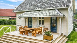 A wooden house with a porch, a table, and benches. - Beautiful home in Hebnes with house sea view (Hebnes)