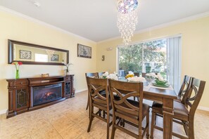 Un coin repas agrémenté d’une cheminée, de chaises en bois et d’une table dressée pour quatre personnes.