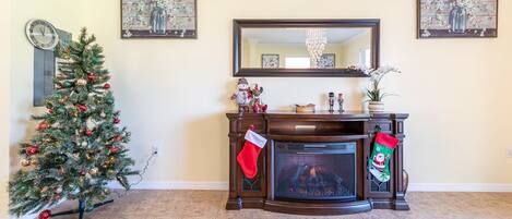 Una sala de estar con chimenea, un árbol de Navidad y decoración navideña.