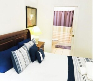 Cozy retreat with a neatly made bed, wooden headboard, and a bedside table with a lamp.