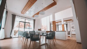 Un espace de restauration moderne avec un plafond en bois, de grandes fenêtres et une vue sur les arbres aux couleurs automnales.