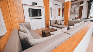 Un salon moderne avec un long canapé, une table basse en bois et un téléviseur à écran plat fixé au mur.