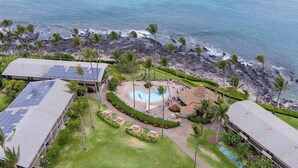 Eine Vogelperspektive zeigt ein Resort mit Schwimmbad, Solaranlagen und einem Strandbereich.