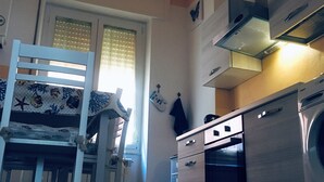 Une cuisine compacte avec un coin repas, comprenant une chaise en bois, une table à manger et un four encastré.