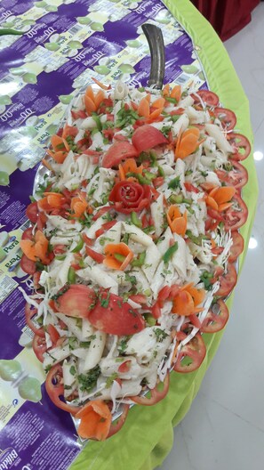 Ein Salat mit verschiedenen Gemüsesorten und Kräutern auf einem Tisch mit einer violett-grünen Tischdecke.