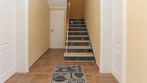 Ein Flur mit einer Treppe, die zu einer Tür führt, einem Teppich mit dem Aufdruck 'I love London' und einem gefliesten Boden.