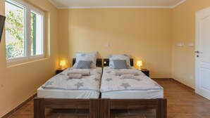 Ein Doppelbett mit sternenmusterbezogener Bettwäsche, zwei Nachttische mit Lampen und ein Fenster mit Blick ins Grüne.