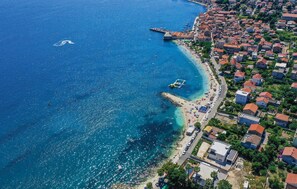 Vista aérea de un pueblo costero con playa, barcos y un muelle.