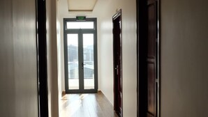 A corridor with wooden flooring and doors on both sides, leading to a bright exit. - Happy View Hotel (Tan Hai)