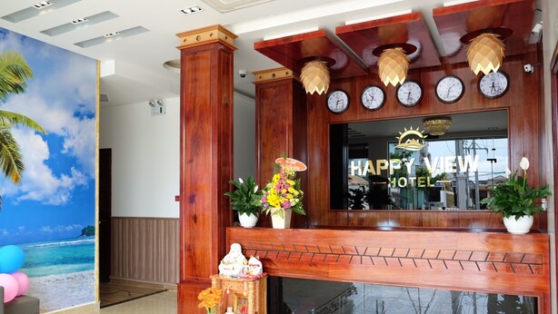A hotel reception area with a wooden facade, a large window displaying the hotel's name, and a tropical mural on the wall. - Happy View Hotel (Tan Hai)