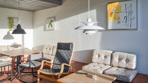A modern living room with a sofa, armchairs, a dining table, and artwork on the walls. - Feriehotel Tranum Klit (Brovst)