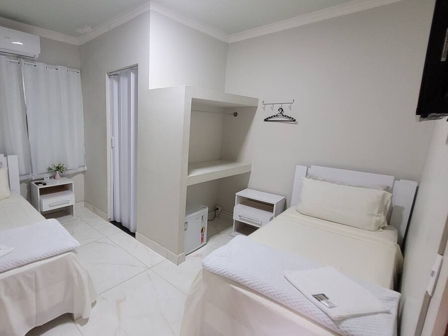 Habitación de hotel con dos camas, un armario, un escritorio pequeño y un espejo.