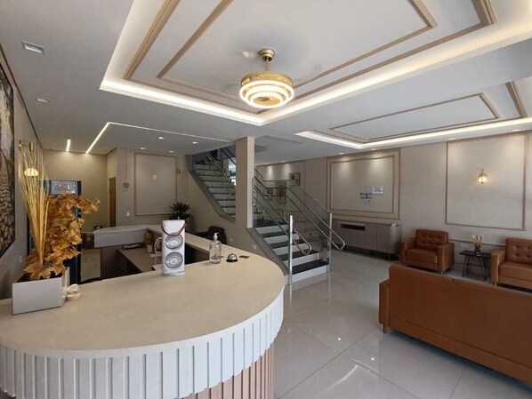 A modern hotel lobby with a reception desk, seating area, and staircase. - Hotel Hiperion (Maringá)
