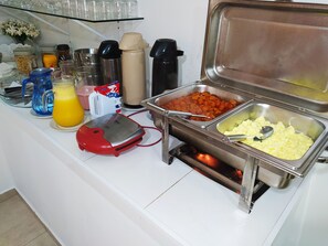 A buffet setup with various food items and beverages. - Hotel Hiperion (Maringá)