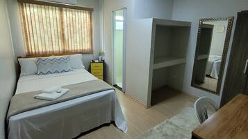 Un dormitorio con cama, mesita de noche, espejo y un escritorio pequeño.
