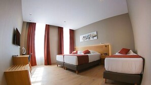 Een hotelkamer met twee bedden, een bureau en een televisie.